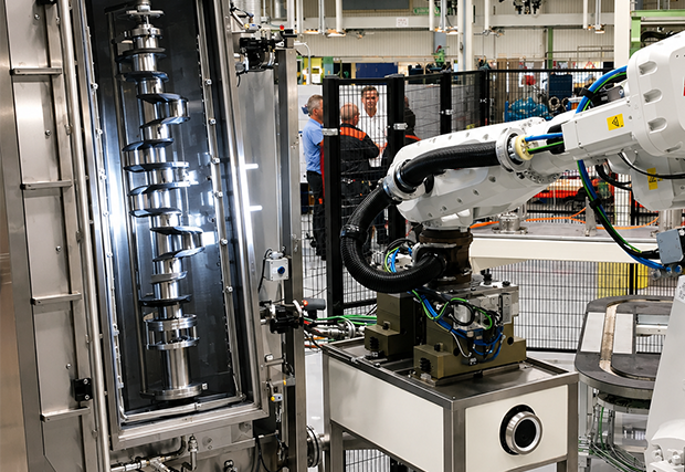 Kurbelwelle, die von einem Roboter vertikal auf eine Teilereinigungsmaschine geladen wird – MecanoFAST